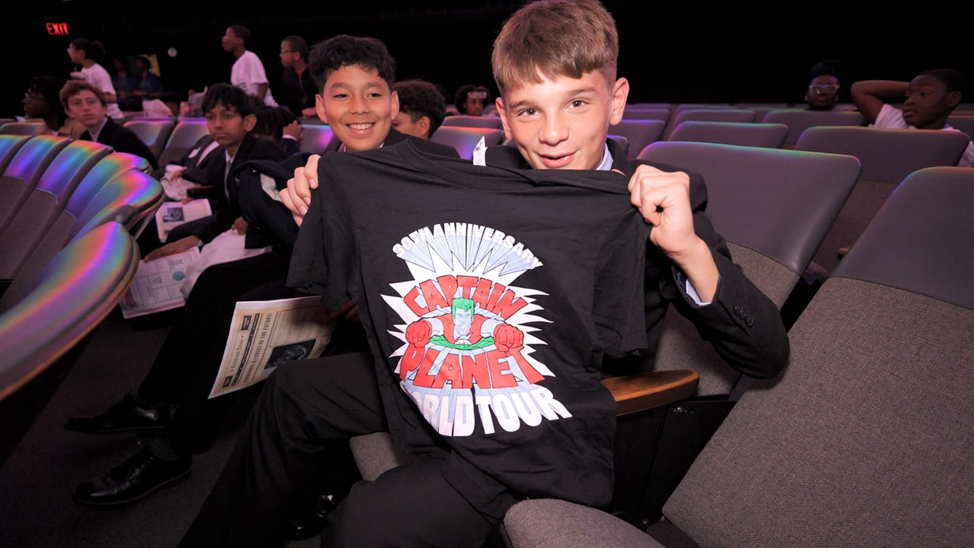 A student shows off their Captain Planet t-shirt they won after having answered a trivia question correctly.