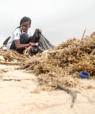 Oluwaseyi Moejoh cleaning up the beach as founder of U-recycle Initiative Africa