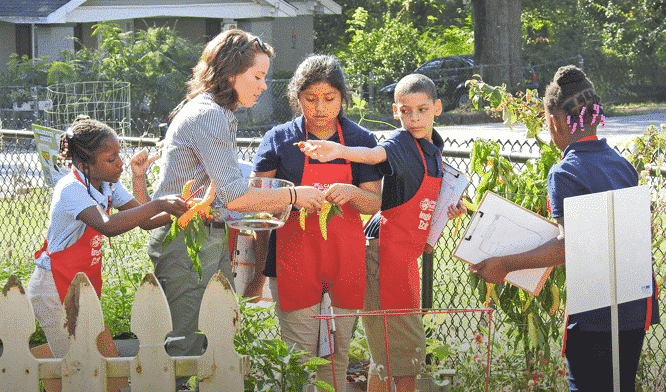 Students in garden with red aprons