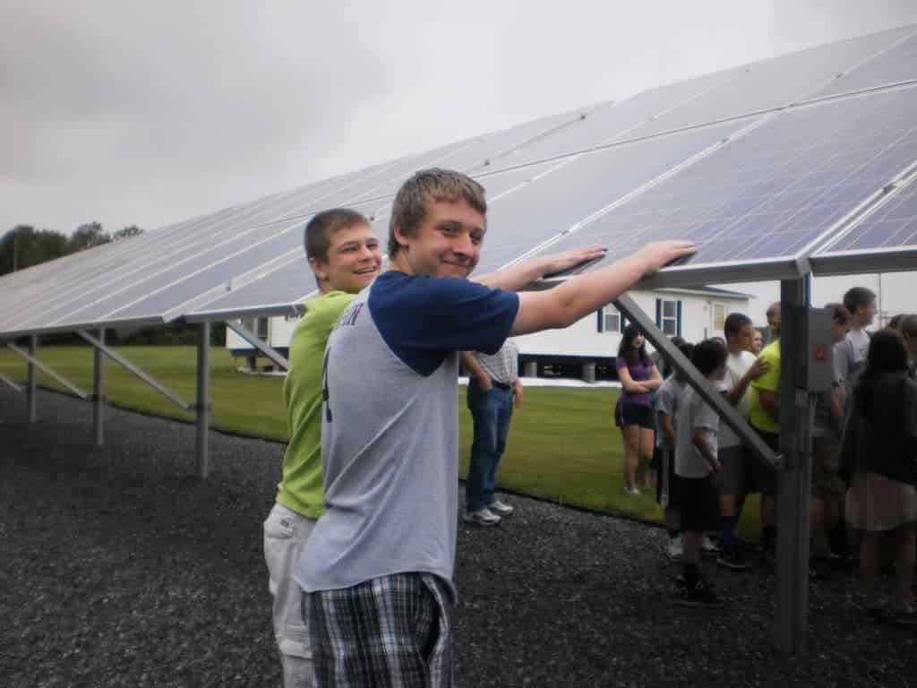 two boys with hands on solar panels