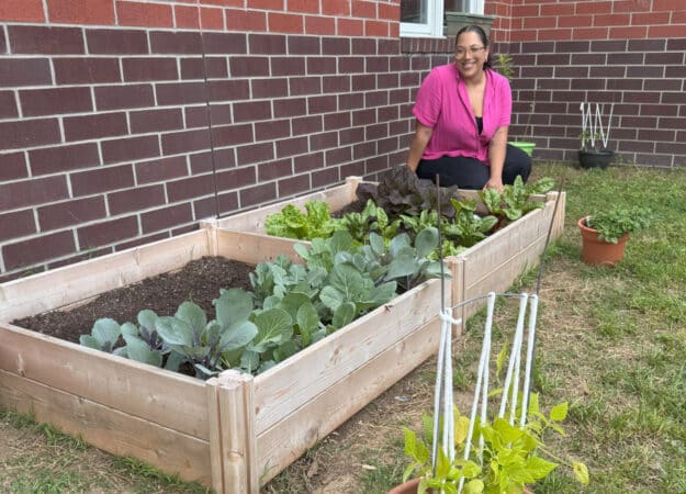 PLG Garden Coordinator, Keziah Silva, at Amqui K-8 Magnet School in Nashville, TN, with some of the garden and the green bean trellis designed by the Amqui kindergarteners.