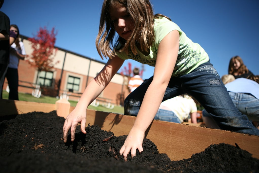 young girl digging in rich soil