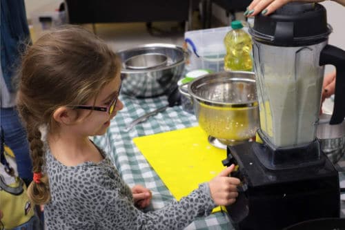 Delighted young student using a mixer to prepare ingredients