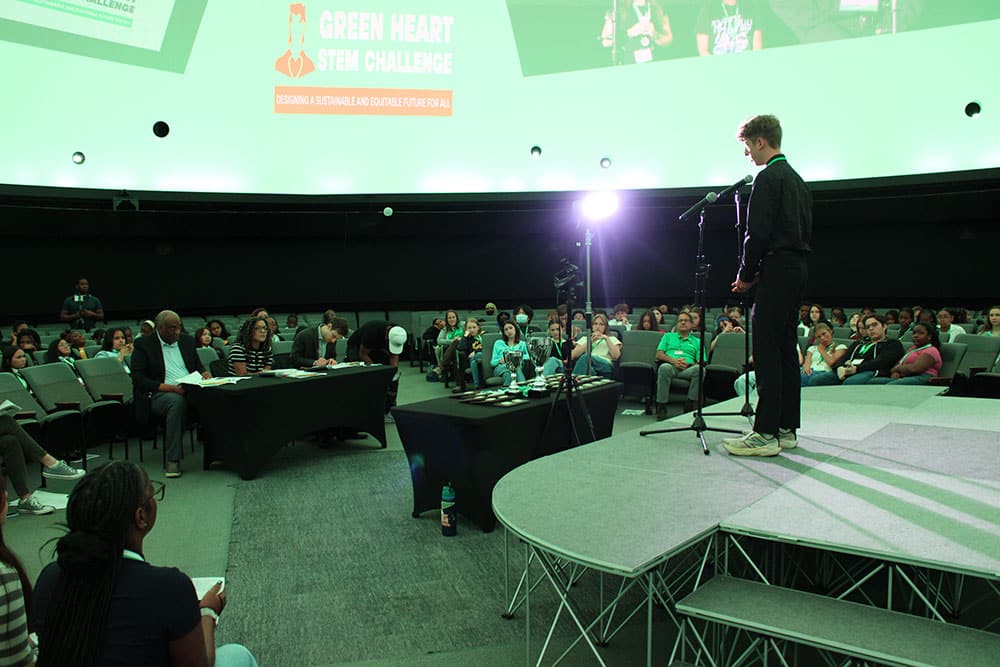 Judges take notes as a student pitches their team's solution