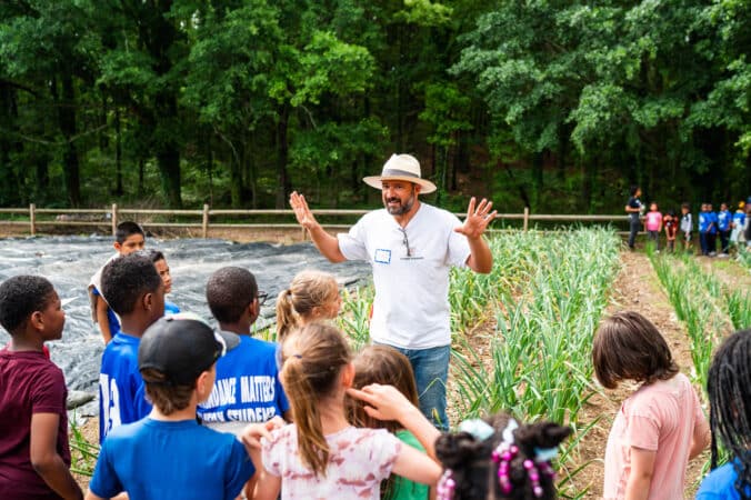 Agro-designer and school gardening expert, Derron “Farmer D” Joffe, explaining farming concepts with young students.