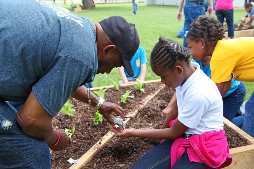 mentor helping young girl plant seeds