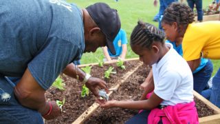mentor helping young girl plant seeds
